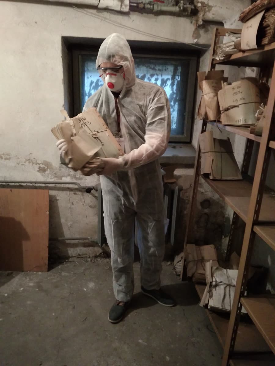 Pracownik w odzieży ochronnej podczas prac przy zniszczonych dokumentach